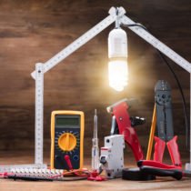 Repair Tools Under The Illuminated House Made With Measuring Tape On The Wooden Table